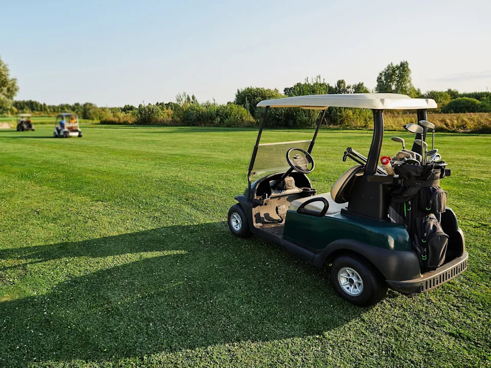 Golf carts lined up on a golf course.