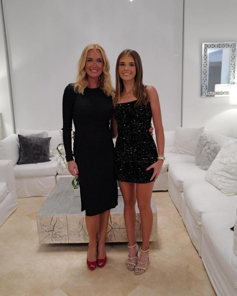 Two women in black dresses pose for a photo.