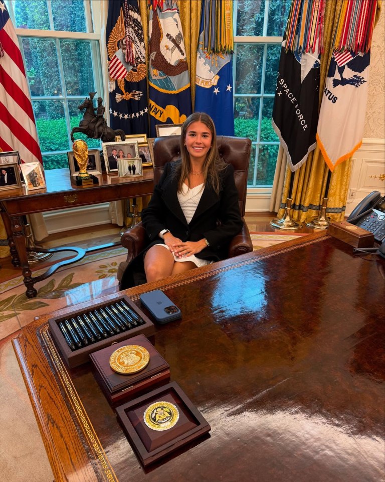 Woman sitting at the Resolute Desk in the Oval Office.