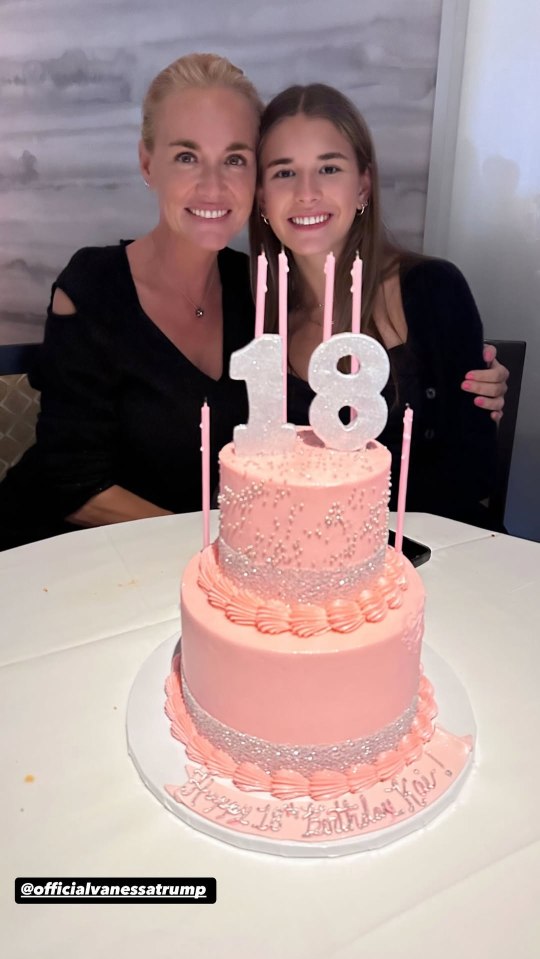 Two women posing with a two-tiered pink birthday cake decorated with the number 18.