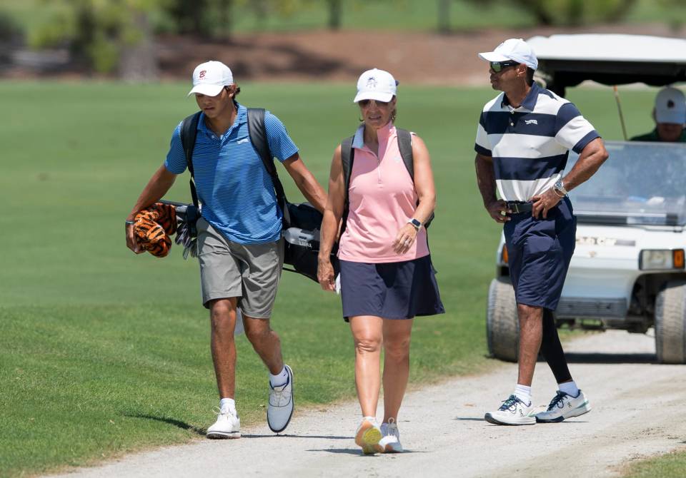 Charlie Woods walking with his father, Tiger Woods, and another person on a golf course.