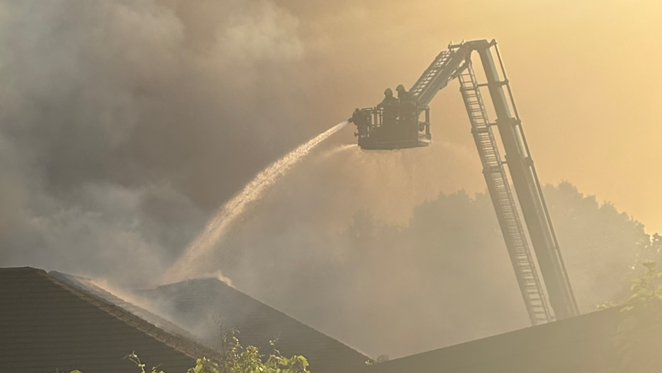 Firefighters using an aerial platform to tackle the blaze with a lot of smoke obscuring the picture.