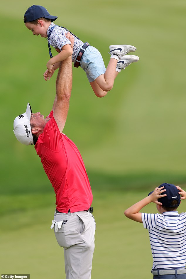 Bradley raises his son, Cooper, in the sky at the 18th green after winning the Travelers