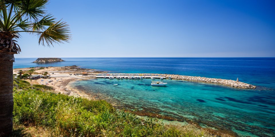 Coastal view of Paphos, Cyprus, with boats in a calm harbor.