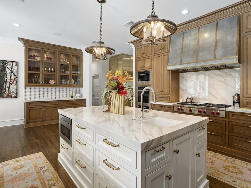 The kitchen has a mix of warm-toned wood cabinetry and marble countertops. Tucked away in...
