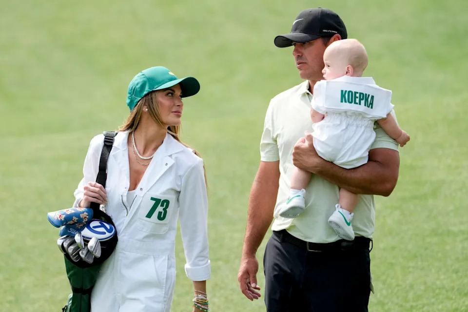 Brooks Koepka carries his son, Crew, while walking near the no. 4 green with his wife, Jena Sims, during the Par 3 Contest at Augusta National Golf Club.© Michael Madrid-USA TODAY Network