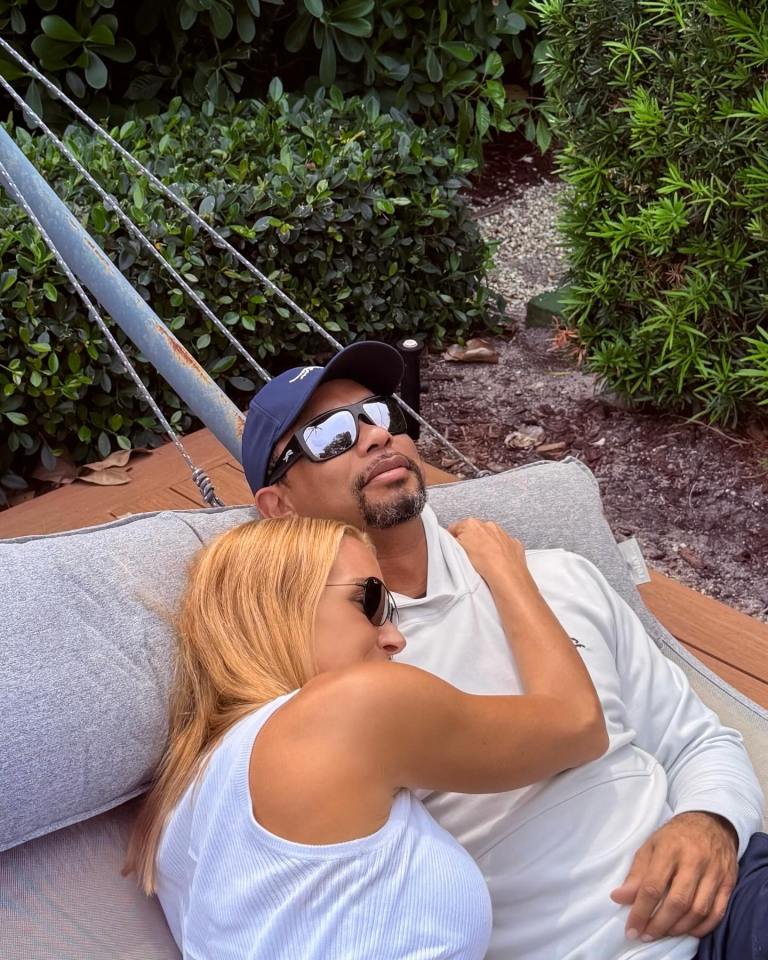 Tiger Woods and a woman cuddling in a hammock.