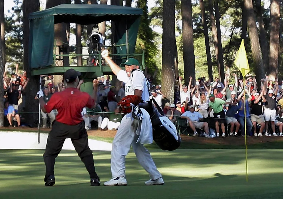 Tiger Woods, left, celebrates with caddie Steve Williams on the 16th green after his chip-in birdie during the 2005 Masters.
