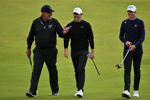 Rory McIlroy, Tom McKibbin and Darren Clarke walk on the course while smiling