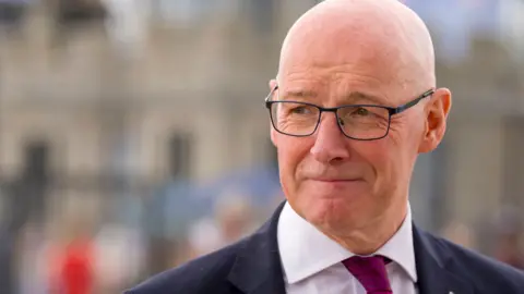 PA Media John swinney in a suit  and twi with glasses and bald head