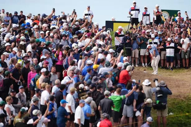 Fans watch Rory McIlroy play from the rough