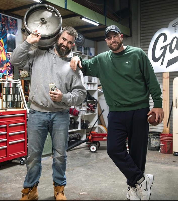 Two men in a garage, one carrying a keg.