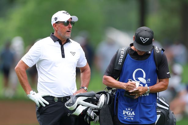 Phil Mickelson talks with his caddie Jon Yarbrough