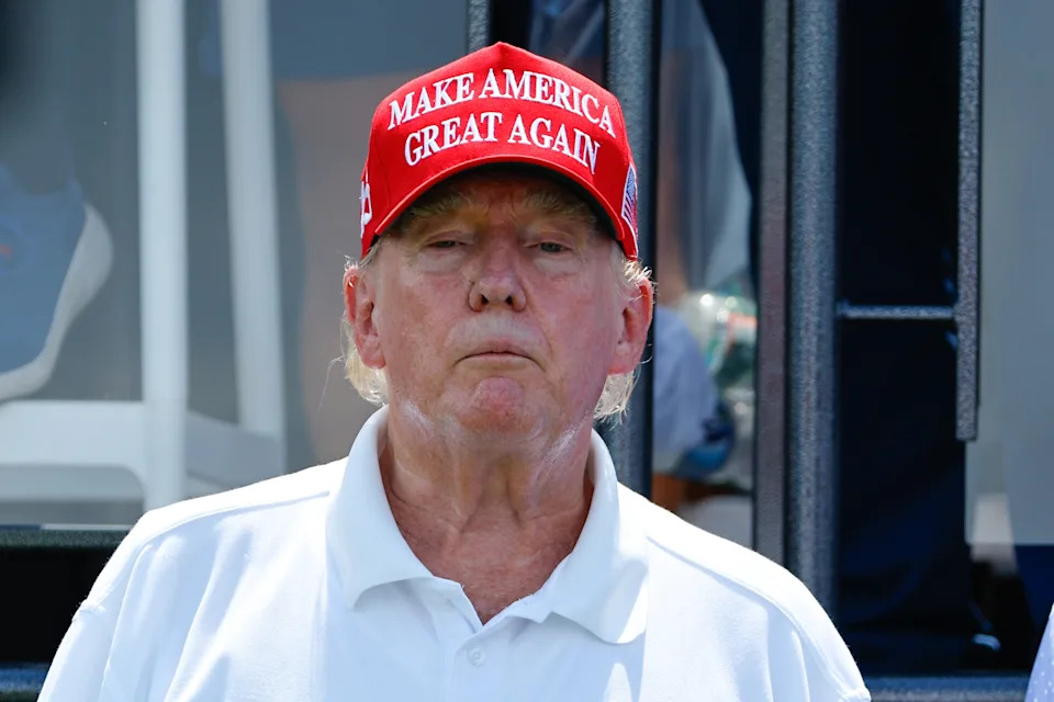 Person in a white polo shirt wearing a red "Make America Great Again" cap, standing outdoors