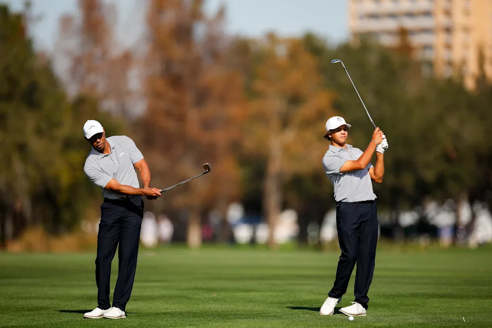 ORLANDO, FLORIDA - DECEMBER 21: Tiger Woods and his son Charlie Woods wait to hit their approach shots on the 18th hole during the first round of the PNC Championship at Ritz-Carlton Golf Club on December 21, 2024 in Orlando, Florida. (Photo by Mike Ehrmann/Getty Images)