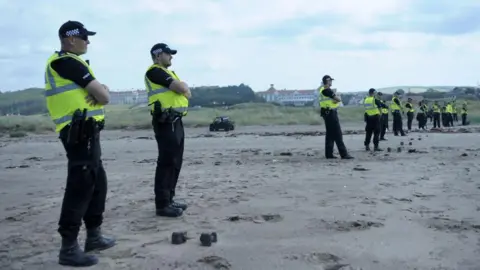 Getty Images A line of Police Scotland officers on a beach  with the Turnberry golf course and hotel visible behind them.