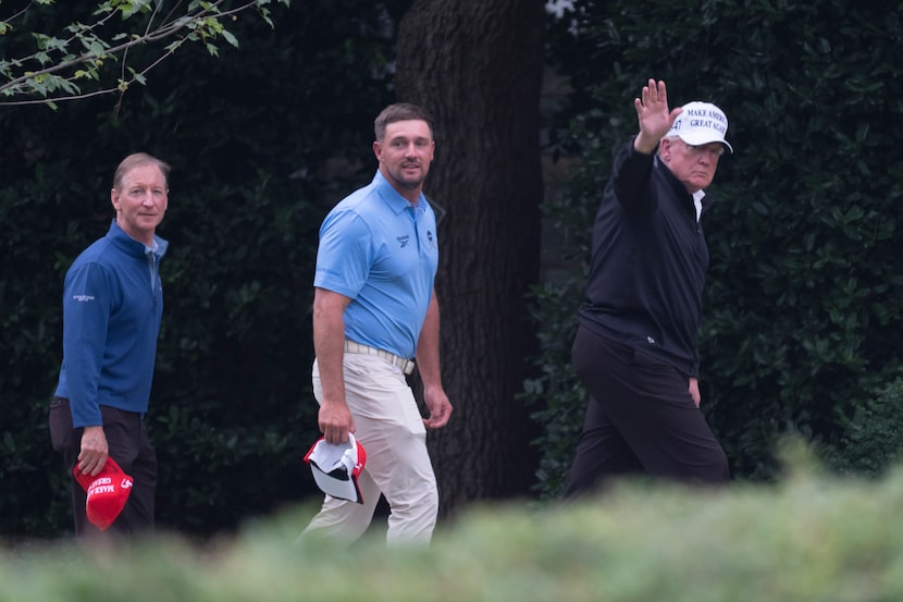 President Donald Trump (right) walks toward the Oval Office as he returns to the White House...