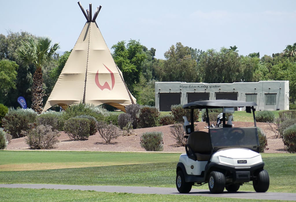 A tipi and a building labeled "Players Academy" with a golf cart in the foreground.