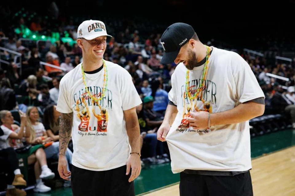 Carson Beck, college football quarterback, left, and Jake Ferguson, NFL tight end, wears shirts in support of their girlfriends, Hanna and Haley Cavinder, during the second quarter of a game on Sunday, Jan. 26, 2025, at Watsco Center in Coral Gables, Fla.