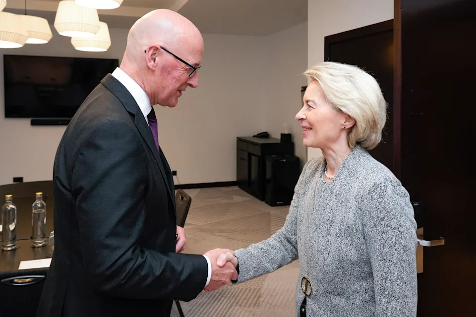 John Swinney, who has a bald head and is wearing a black suit jacket, shakes the hand of Ursula von der Leyen, who has short blonde hair and has grey suit jacket with a gold fastening.