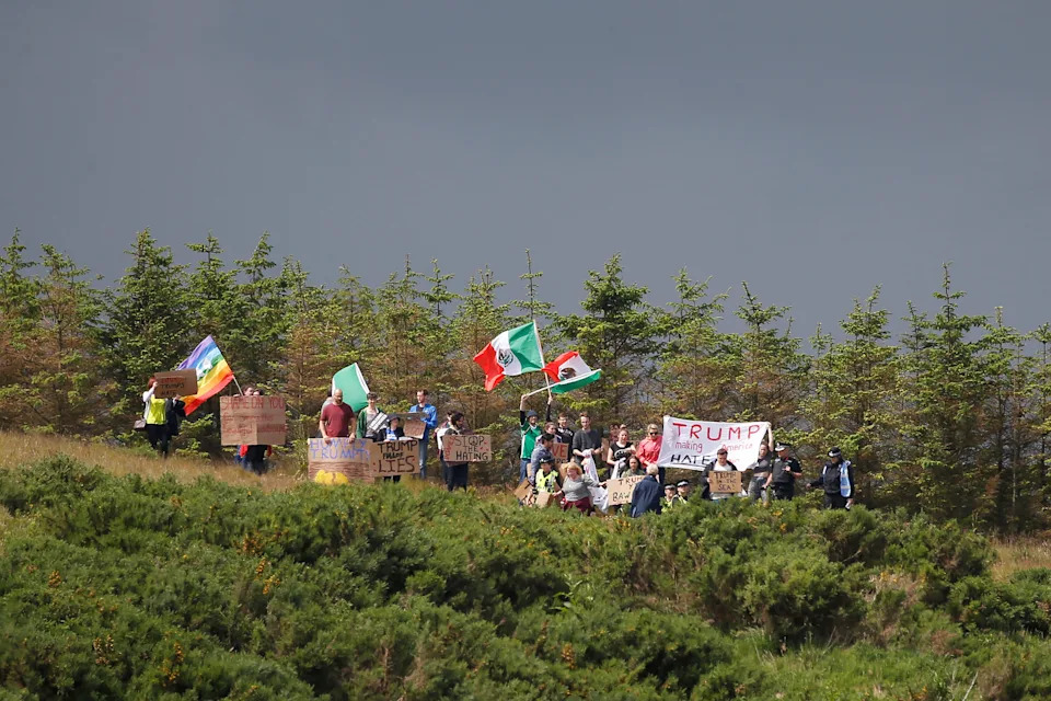 Protesters wave flags and signs on the road leading into Republican presidential candidate Donald Trump's Trump International Golf Links in Aberdeen, Scotland, June 25, 2016. Trump is visiting the property as part of a five-day trip to Scotland starting July 25.