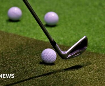 A golf club, poised to be swung towards a golf ball on a simulator