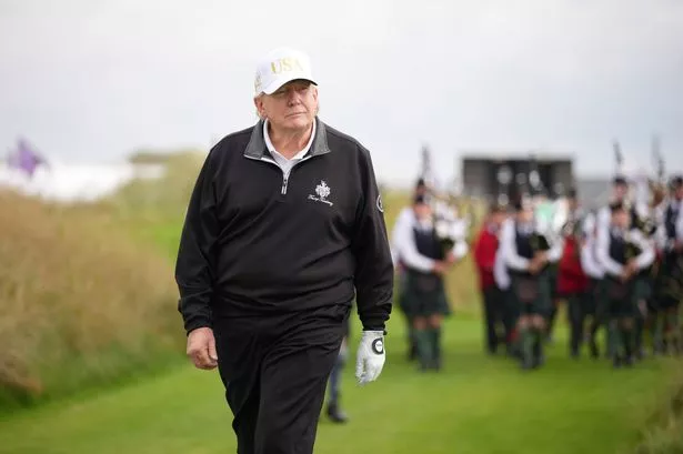 U.S. President Donald Trump reacts as he walks on the golf course