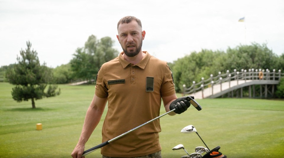 Ukrainian serviceman holding a golf club on a golf course.