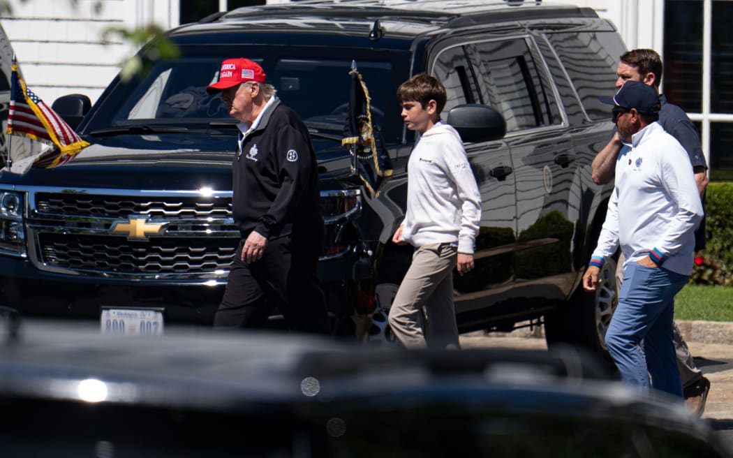 President Donald Trump walks with his grandchild Spencer Trump after golfing at Trump National Golf Club in Sterling, Virginia.