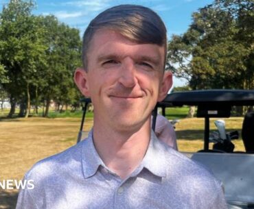 David Gascombe smiles at the camera, he has light brown hair in a side part and is wearing a lilac shirt. There is a golf buggy in the background.
