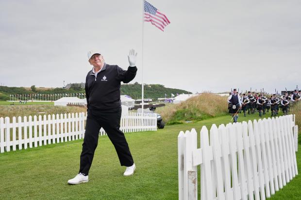 President Donald Trump arrives, followed by a bagpiper band, at...
