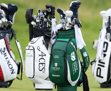 four golf bags standing up on a golf course