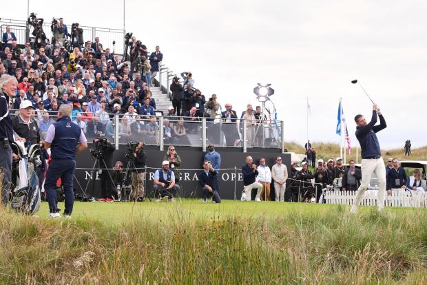 Eric Trump tees off as President Donald Trump, left, stands,...