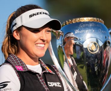 Brooke Henderson smiles while holding a large silver trophy