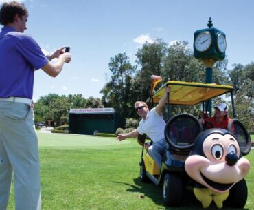 Two people posing near a Mickey Mouse golf cart at Walt Disney World Resort