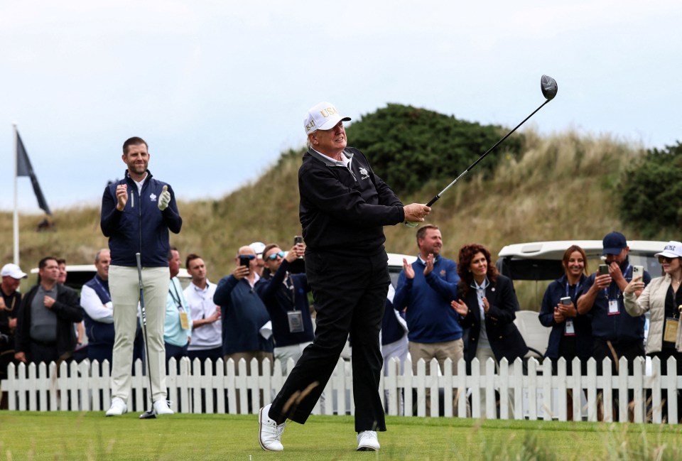 Eric Trump applauds as his father, Donald Trump, tees off at a golf course.