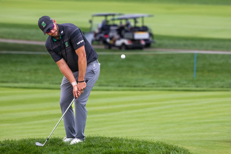 Dean Burmester chips a golf ball.