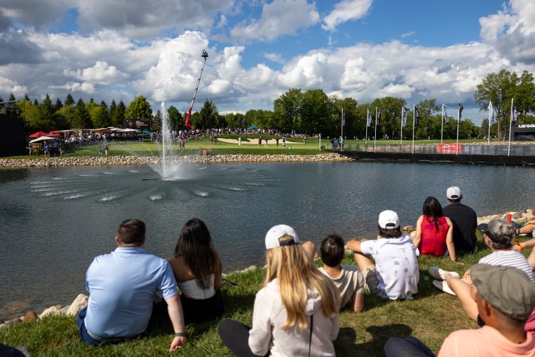 People sit near a pond with a fountain.