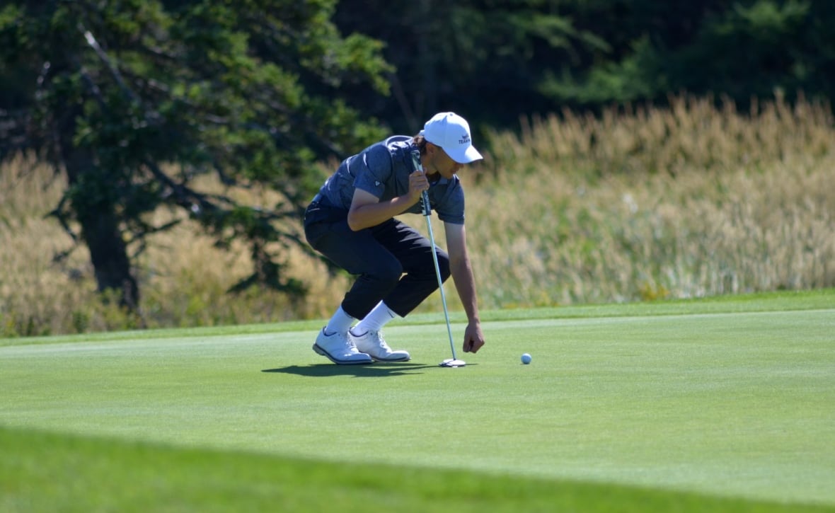 A golfer standing on a putting green.