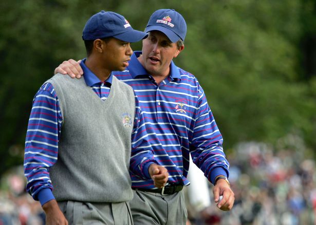 Tiger Woods and Phil Mickelson walk off the 18th green during their afternoon foursome match against Darren Clarke and Lee Westwood