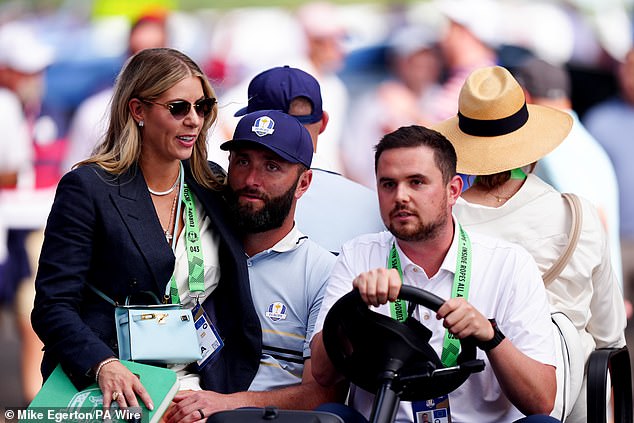 Kelley Cahill, the wife of Spanish golfer Jon Rahm, sits on his lap as they ride on a golf cart