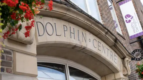 Darlington Borough Council The exterior of the Dolphin Centre with flowers coming over the top left of the pale stone archway.
