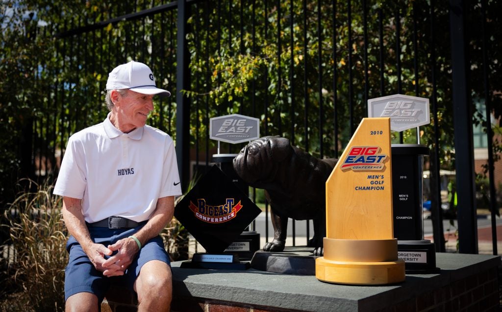 An older Caucasian man looking at some trophies next to a Jack the Bulldog statue
