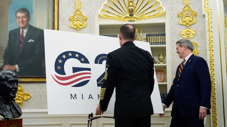 A military aide places a G20 sign in the Oval Office as Treasury Secretary Scott Bessent walks past as President Donald Trump speaks in the Oval Office of the White House, Friday, Sept. 5, 2025