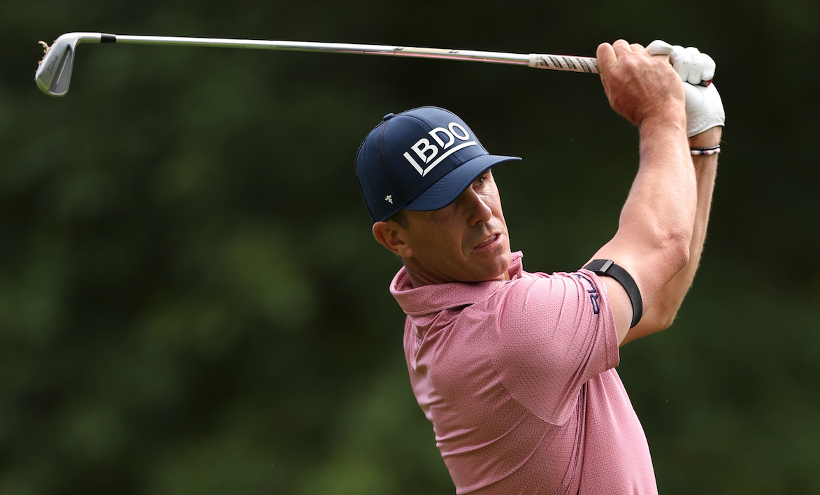 Billy Horschel plays an iron shot wearing a pink polo and navy blue cap