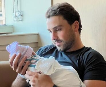 L'homme tient un nouveau né dans ses bras.