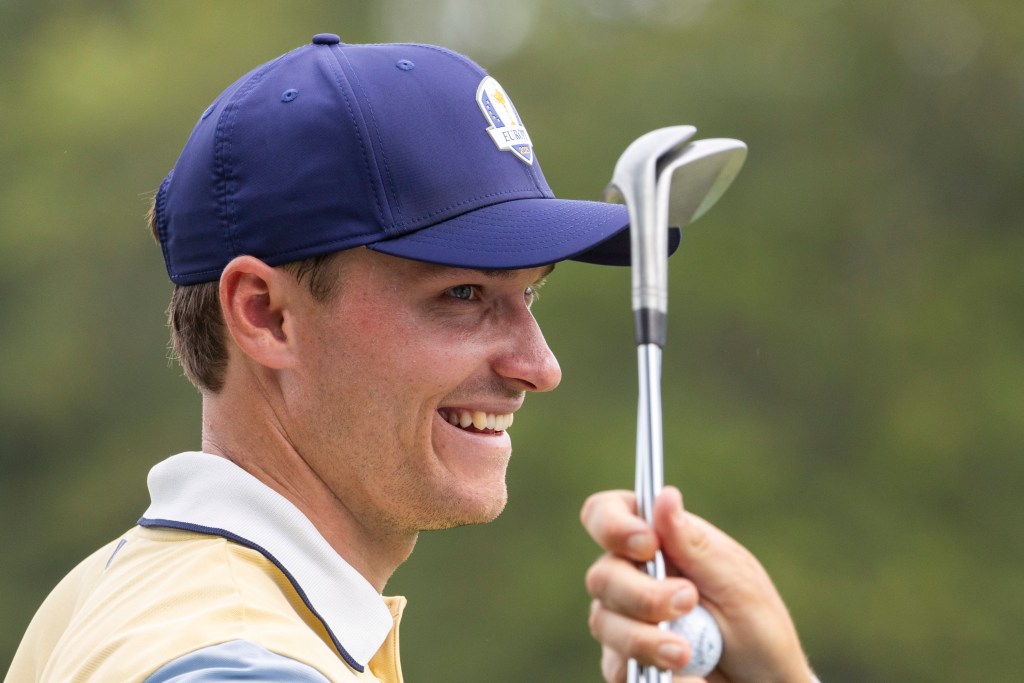 Ludvig Aberg smiling while holding golf clubs.