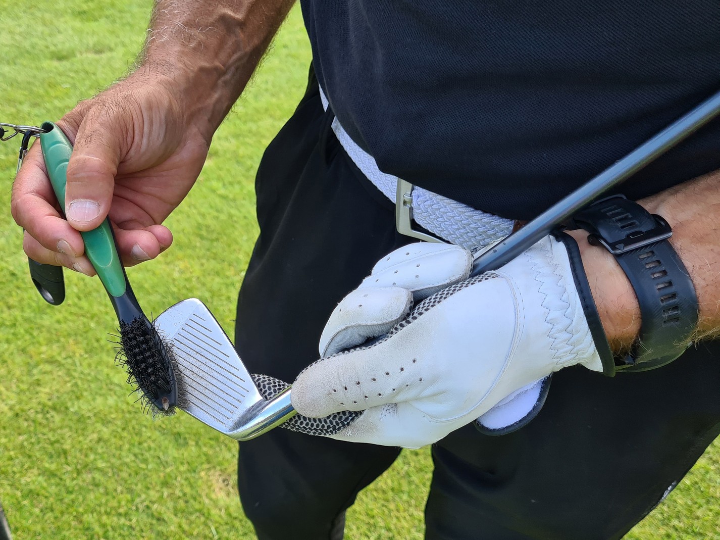 golfer cleaning club with brush