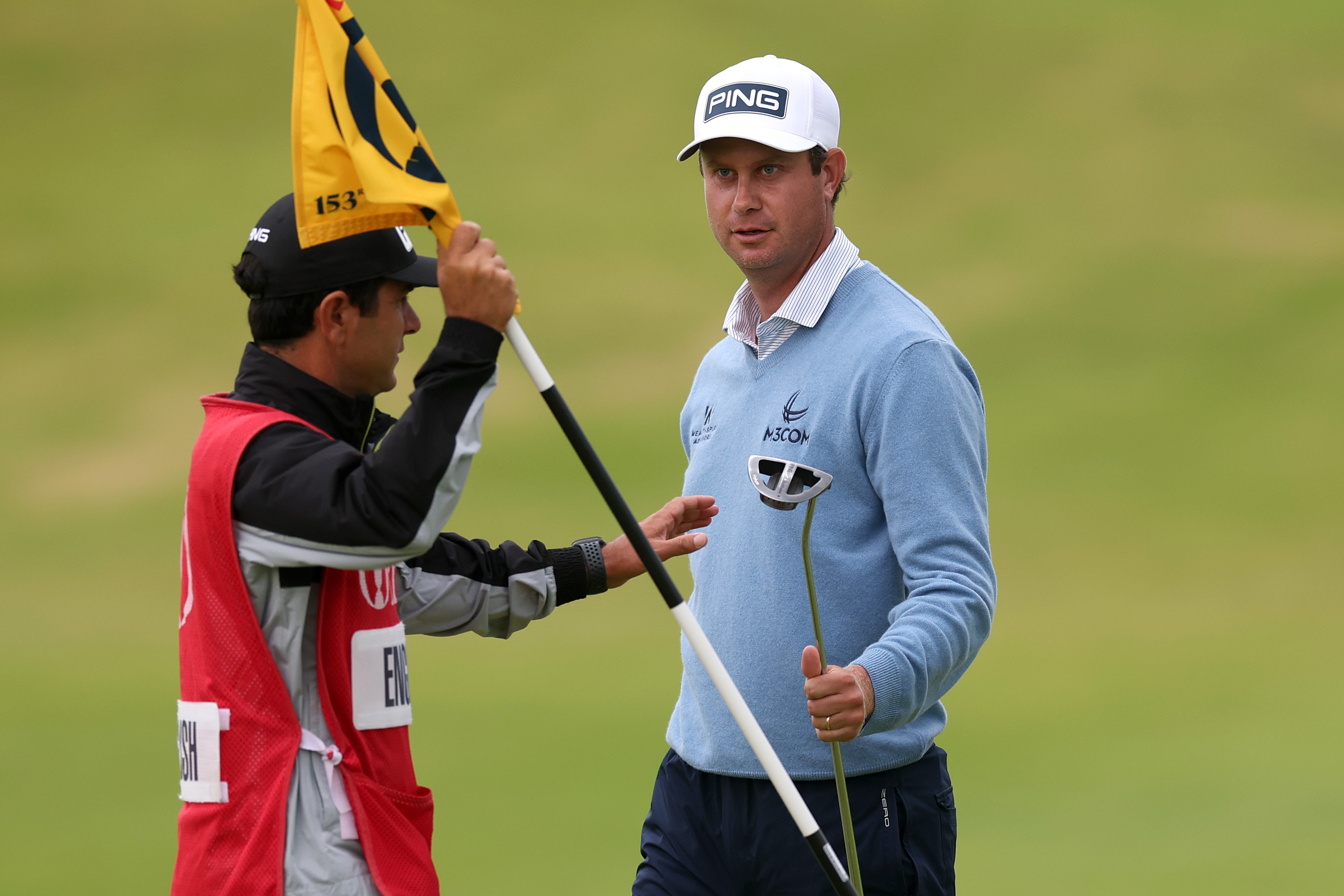 Harris English hands his putter to his caddie