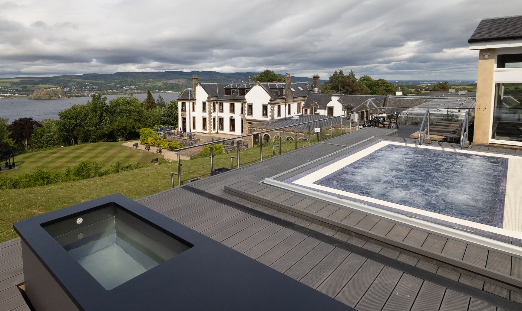 Outdoor spa with a hot tub and a house in the background.